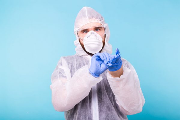 Professional for disinfection efforts. Epidemiologist man puts on protective suit and gloves. Coronavirus, covid-19 and pandemic concept