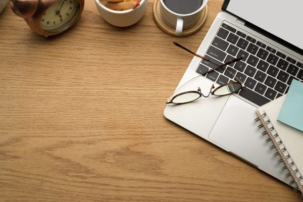 Top view of wooden table with laptop, stationery, decorations and copy space in home office room